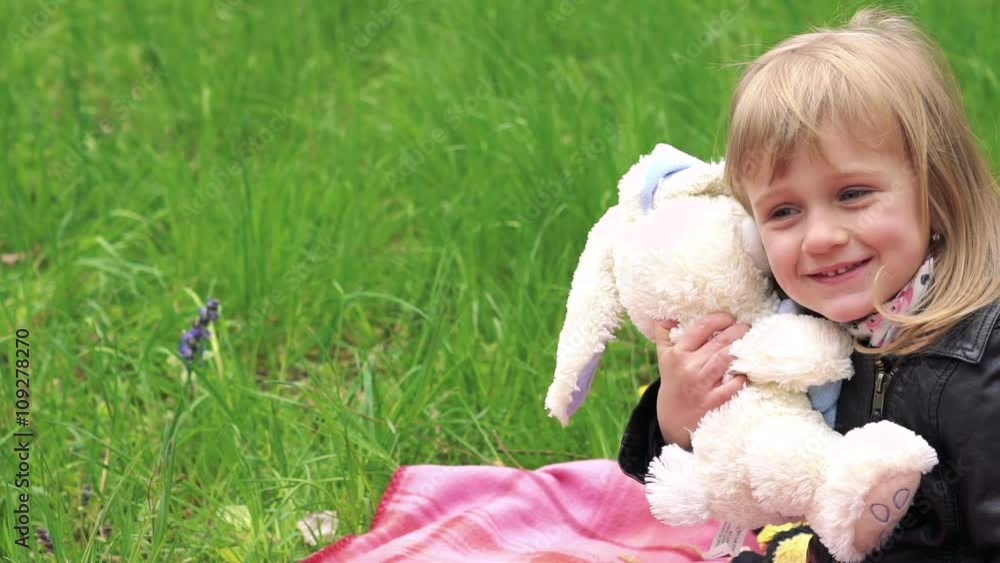 Little girl's playing with soft toy on a lawn in a park. Slowly Little girl's playing with soft toy on a lawn in a park. Slowly