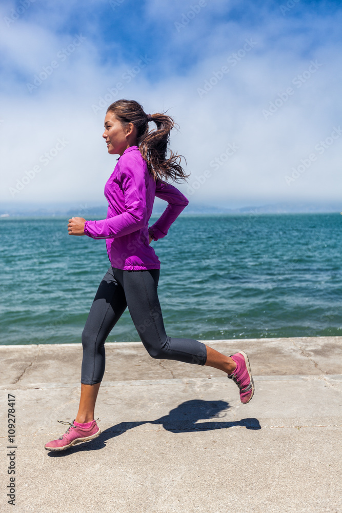 Woman running on waterfront harbour pier in San Francisco, California, USA.  Mixed race fit fitness sport model in spring / autumn running clothing  outfit. Smiling happy female athlete runner training. Photos