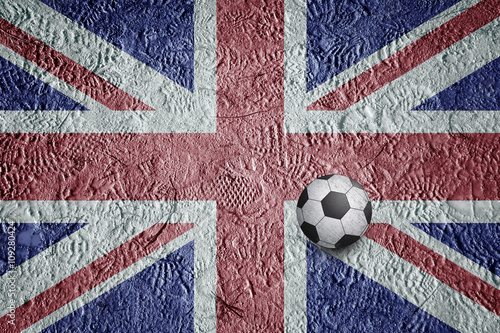 Imprint of the shoes on United Kingdom football field flag with soccer ball.