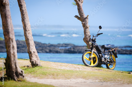 Foto Lonely old moped on the shore of the ocean. Mauritius Island
