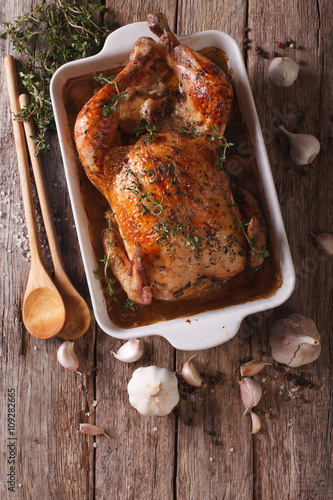 French Food: Chicken with 40 cloves of garlic in the dish for baking close-up. Vertical top view
