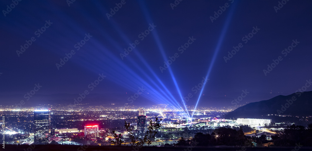 Huge spotlight rays over the night panorama of Los Angeles city - obrazy, fototapety, plakaty 