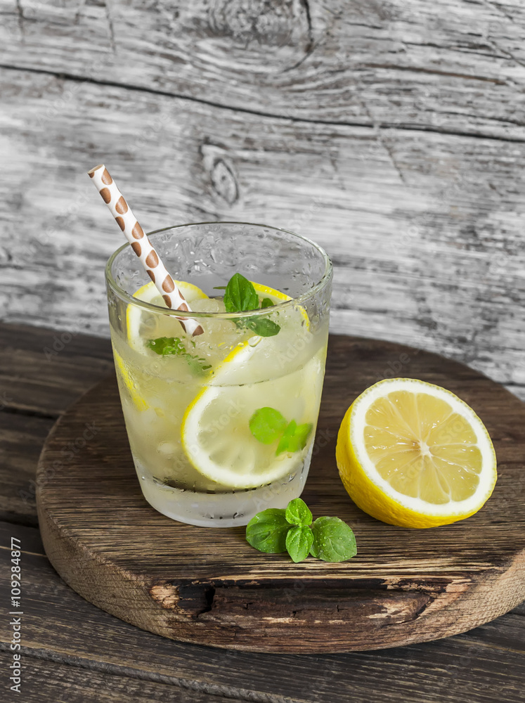 Fototapeta premium Lemon, ginger and mint lemonade on a wooden rustic board. Cold refreshing drink
