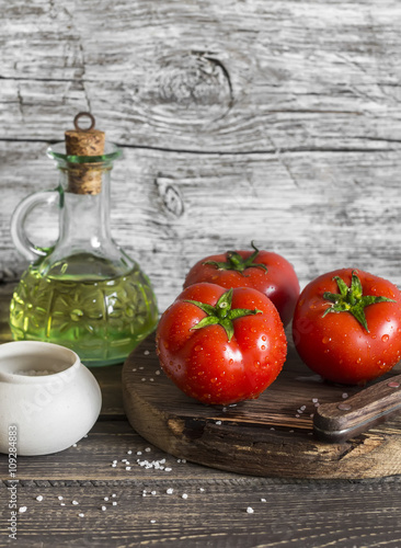 Fresh tomatoes, olive oil and spices on rustic wooden background