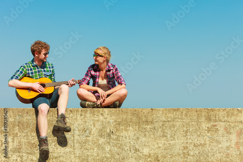 Young man playing guitar to his girlfriend outdoor