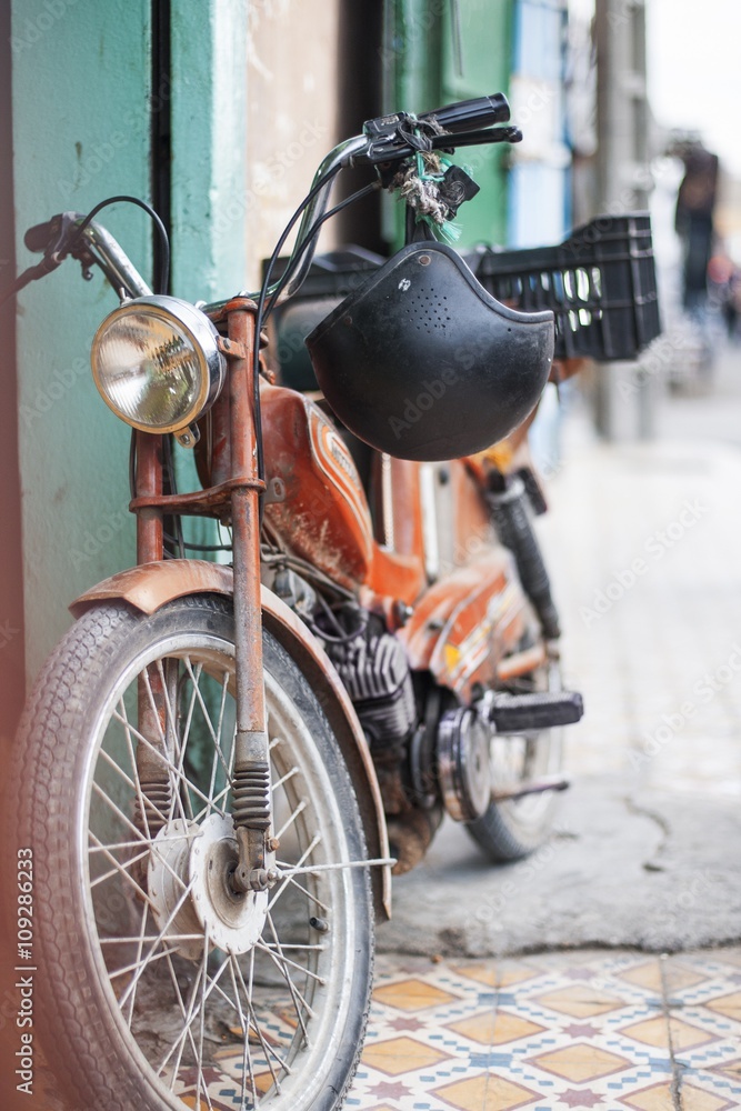 Old retro motorcycle with helmet parked on a little street of Morocco Old retro motorcycle with helmet parked on a little street of Morocco