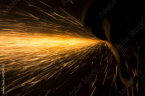 Glowing flow of steel metal spark particles shine in the dark background