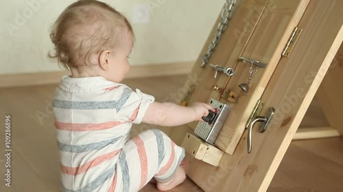 The little boy intently playing with busy board, sitting at the floor photo