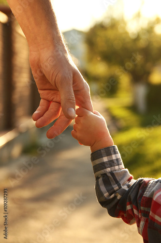 the parent holds the hand of a small child