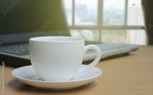 Cup of coffee on the wooden floor and Blurred bedroom window bac