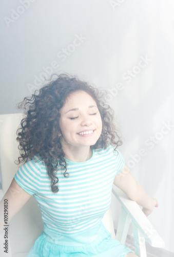 girl with wavy hair on a white chair.