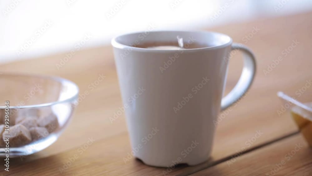 hand adding sugar to cup of tea or coffee hand adding sugar to cup of tea or coffee
