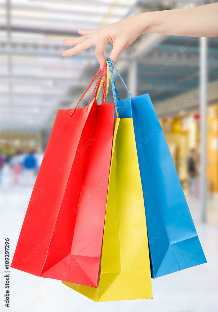 Woman hand holding shopping bags with shopping mall background Woman hand holding shopping bags with shopping mall background