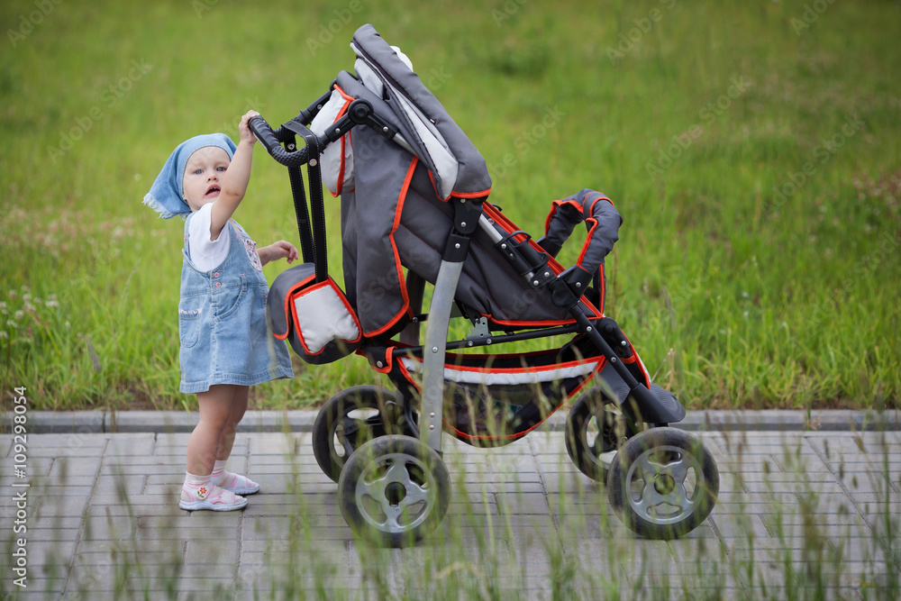 Obraz premium little funny girl with baby carriage