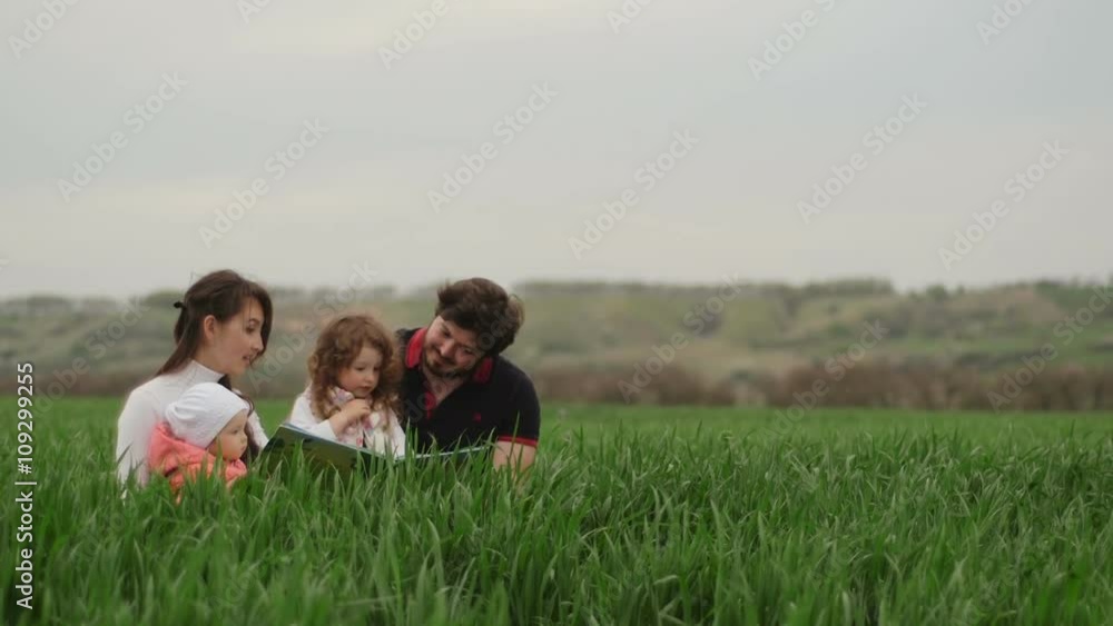 family with children reading a book in the country family with children reading a book in the country