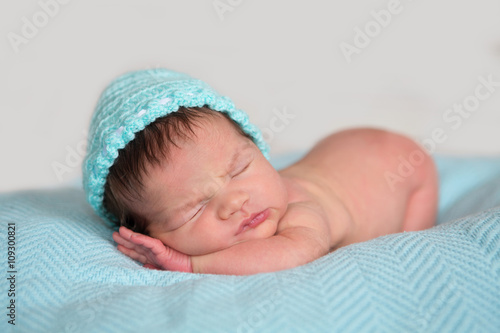 sleeping newborn baby in a hat on a blanket 