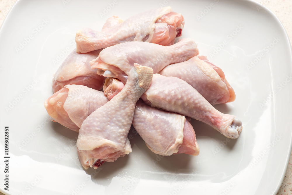 Raw chicken legs on white plate Raw chicken legs on white plate