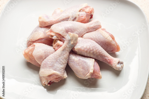 Raw chicken legs on white plate