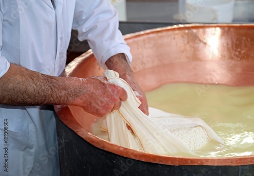 Tableau sur toile Senior cheesemaker collects the cheese with the tarp from the co