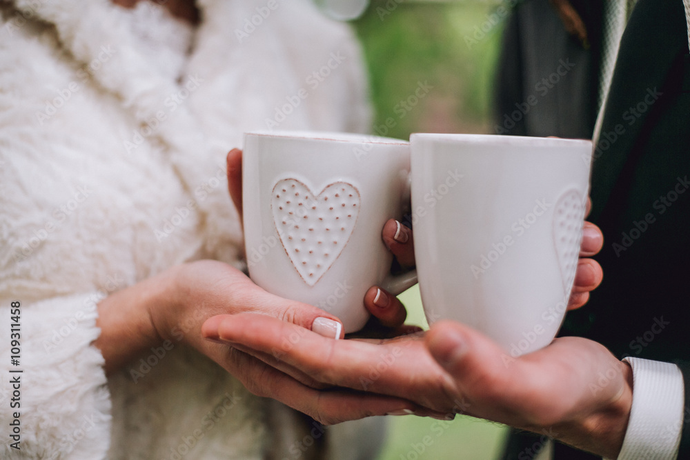 Women's and men's hands with wedding rings with two cups of coffee Women's and men's hands with wedding rings with two cups of coffee