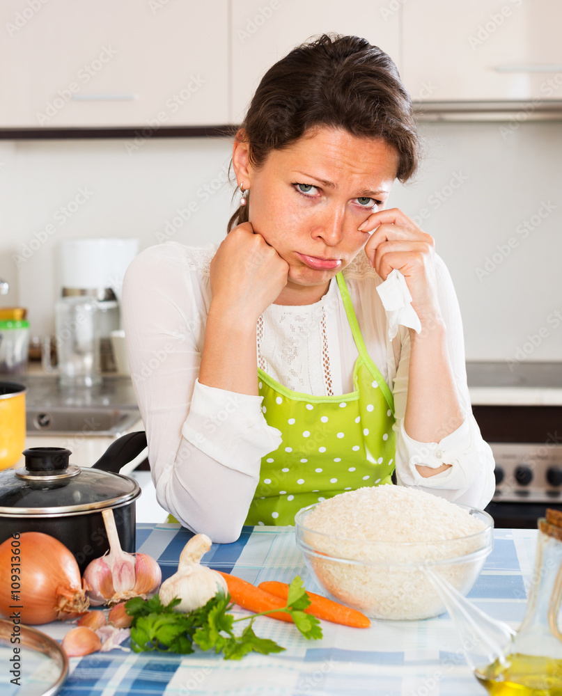 Pensive woman cooks rice with vegetables
