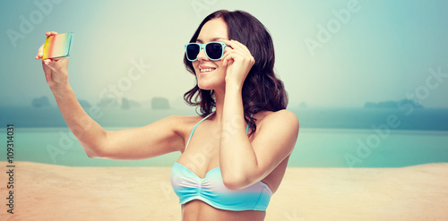 woman in swimsuit taking selfie with smatphone