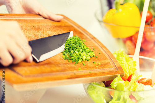 close up of woman with chopped onion cooking salad