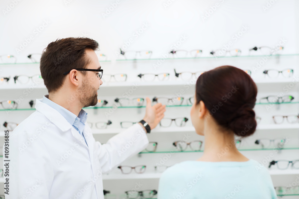 Fototapeta premium woman and optician showing glasses at optics store