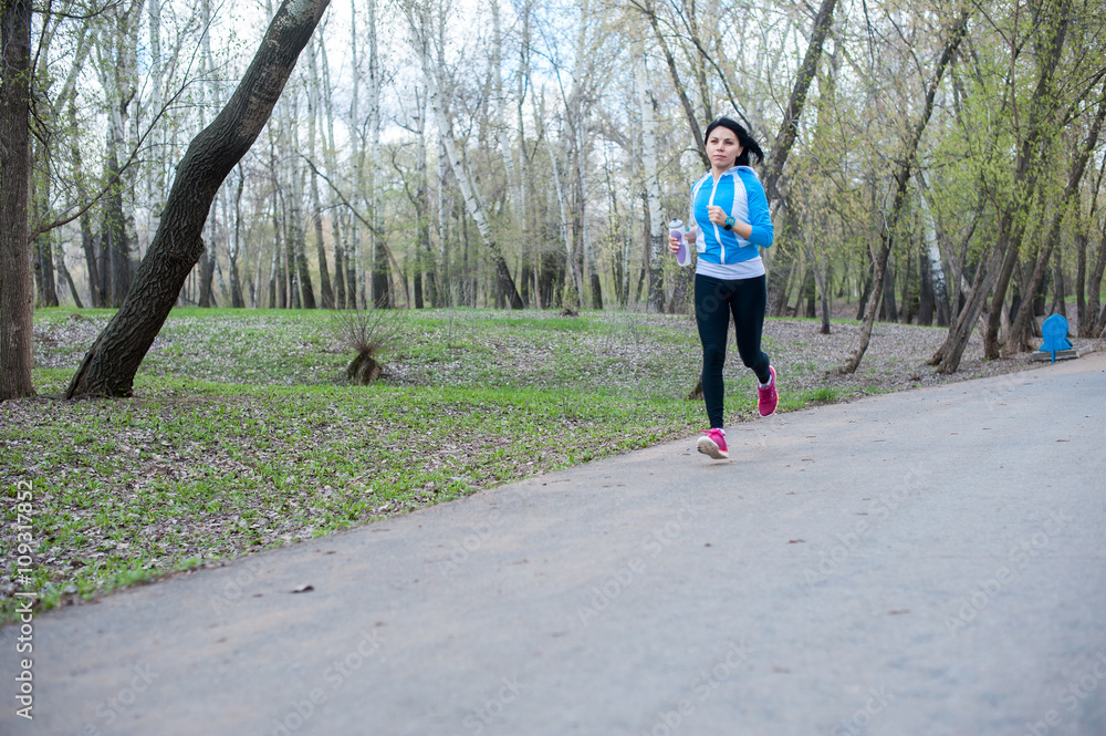 Fototapeta premium Young woman in black tights running around the Park