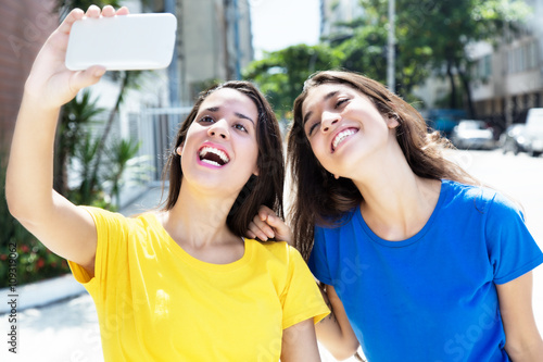 Zwei Freundinnen in bunten Shirts machen Selfies