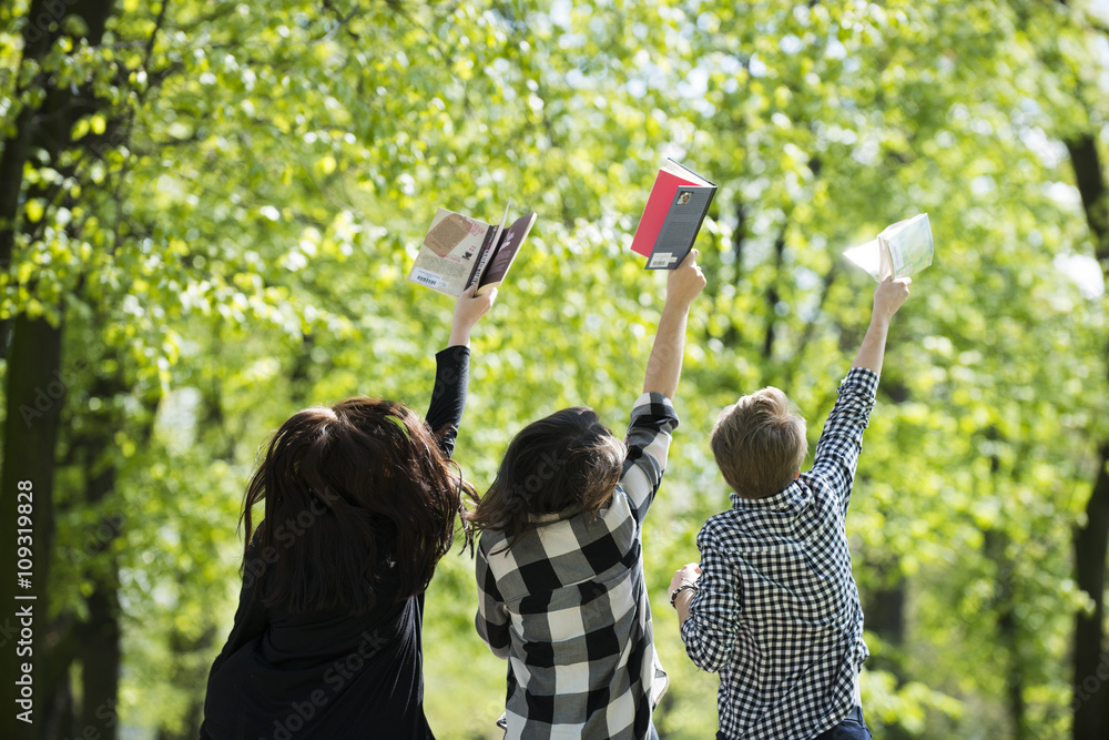 Nastolatki z radością czytają książki w parku wiosną na świeżym powietrzu - obrazy, fototapety, plakaty 
