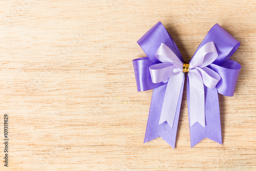 Purple ribbon bow on wooden background