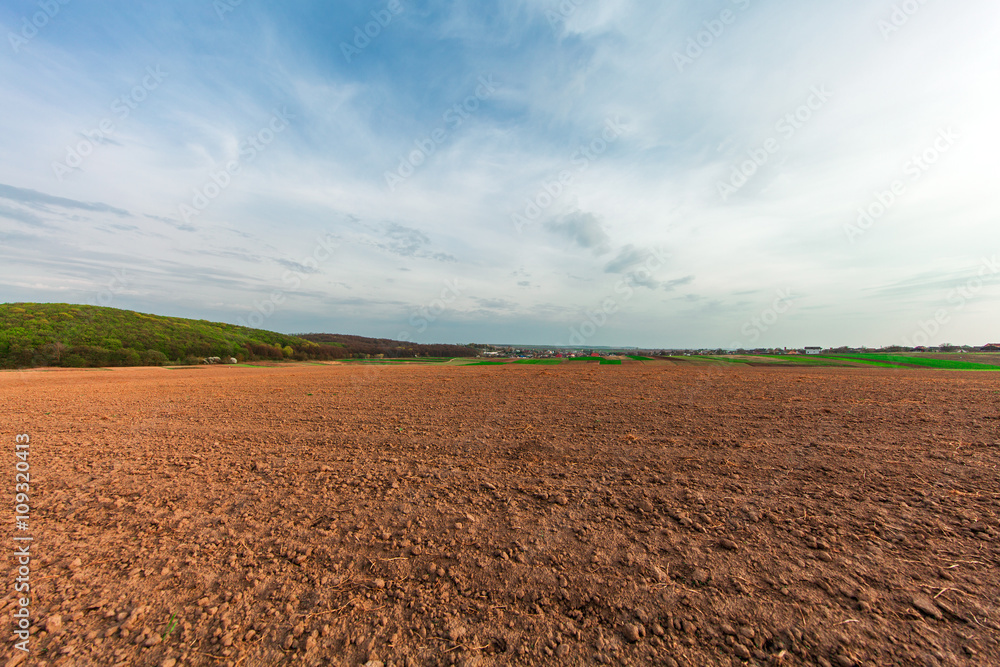 plowed field and cloudy sky in sunset