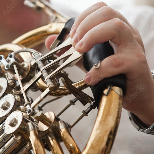 The fingers of the musician playing the French horn closeup