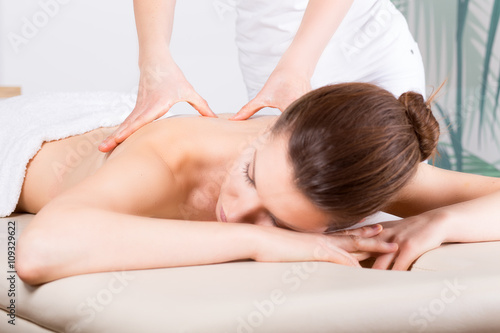 Close-up of young woman receiving back massage/ Close-up image of a young woman who laying on her stomach. She is receiving a back massage.
