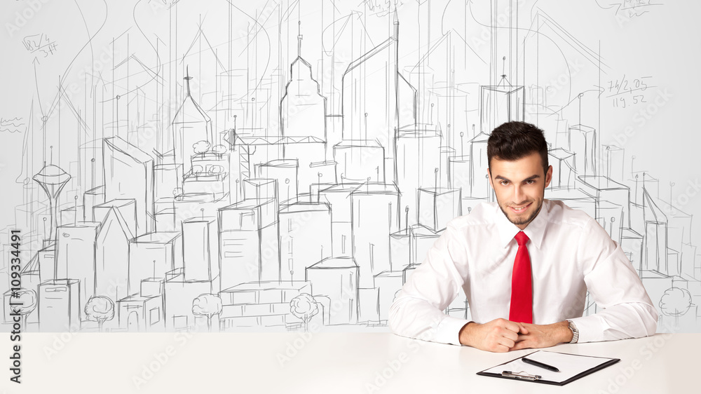 Businessman sitting at the white table with hand drawn buildings Businessman sitting at the white table with hand drawn buildings