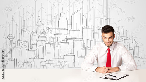 Businessman sitting at the white table with hand drawn buildings