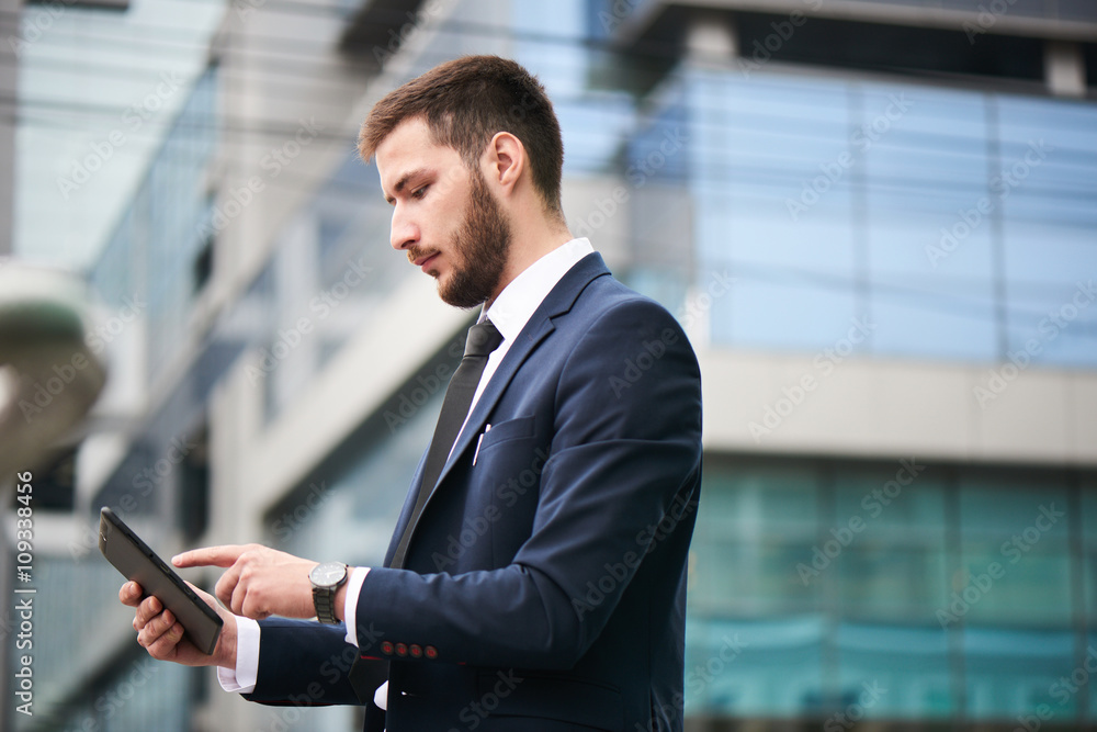 Businessman holding tablet on background of buildings with glass facades Businessman holding tablet on background of buildings with glass facades