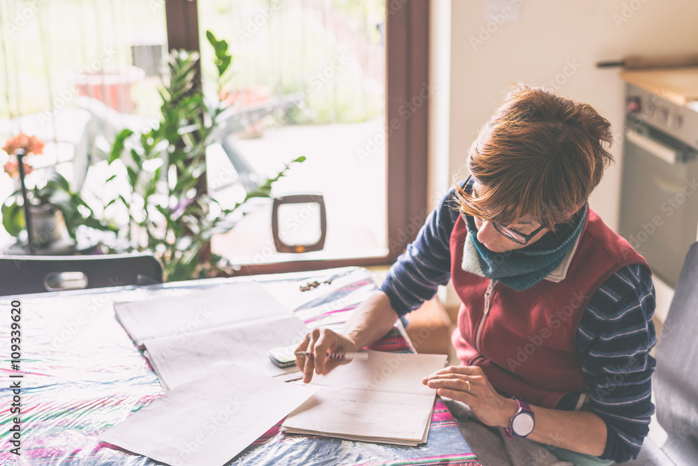 Woman working at home, reading and handwriting documents Woman working at home, reading and handwriting documents