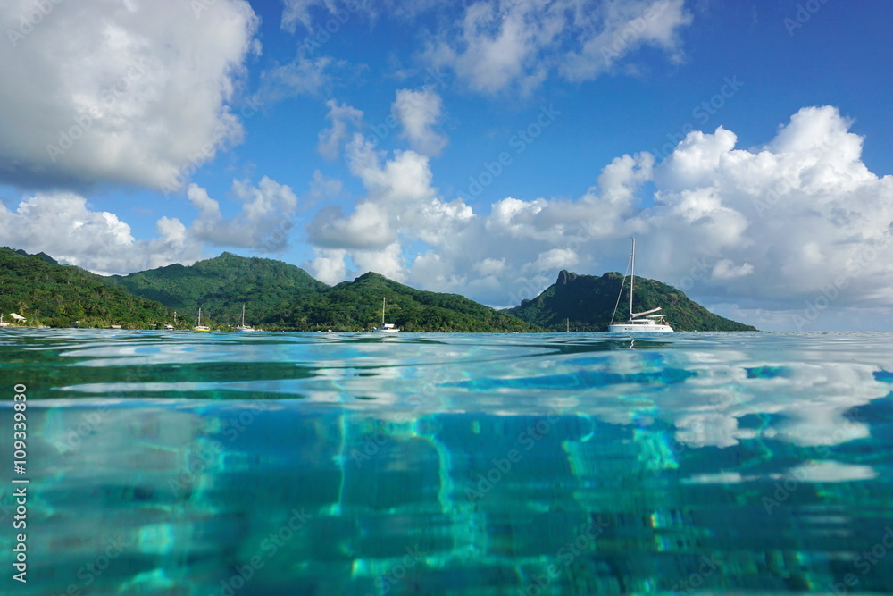 Coastal landscape of Huahine island near the village of Fare, seen from calm water surface of the lagoon, Pacific ocean, French Polynesia