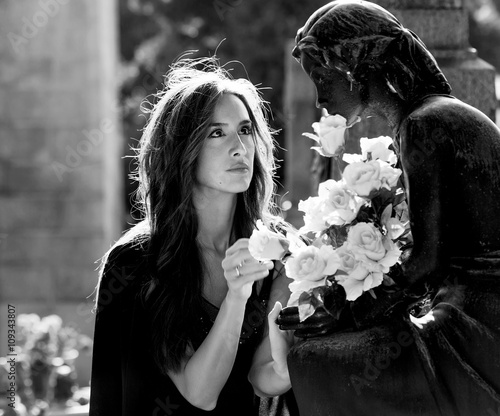 Woman in graveyard giving flowers to the loved one monochrome