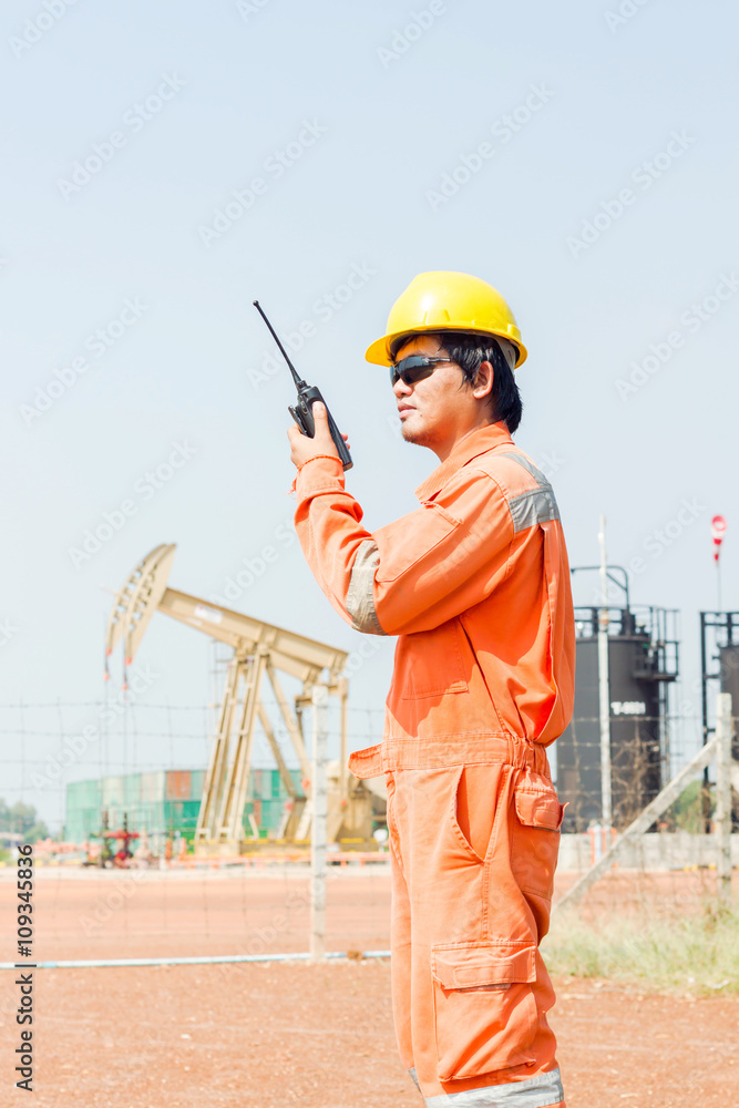man holding walkie-talkie radio in hand, communication in oil field site man holding walkie-talkie radio in hand, communication in oil field site