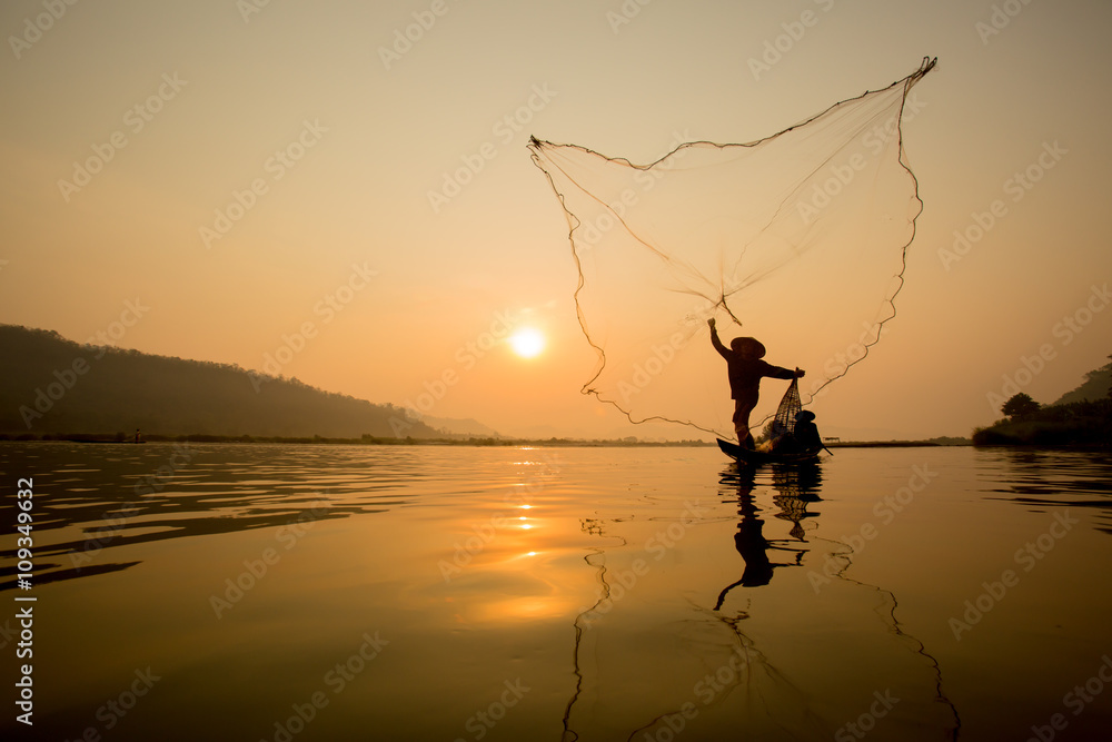 fisherman throwing fishing net during sunset