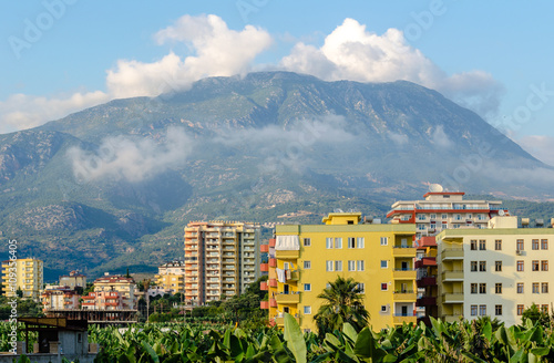 Modern Mediterranean city on the background of mountains and clouds.
