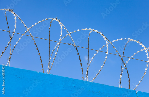 Barbed wire on the fence against a blue sky background