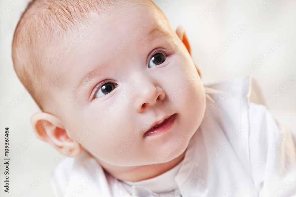 newborn baby in a beautiful white dress on a light background , portrait .