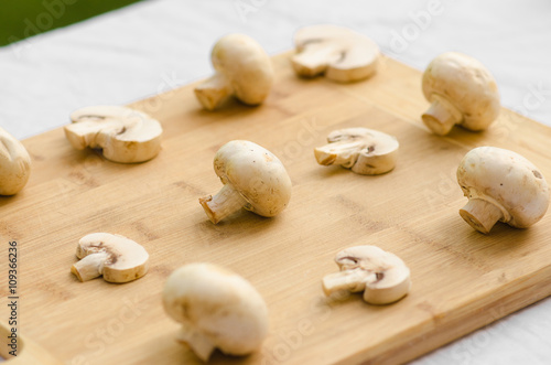 Mushrooms and Food theme: man preparing porcini mushrooms on a wooden board on a background of green grass in summer