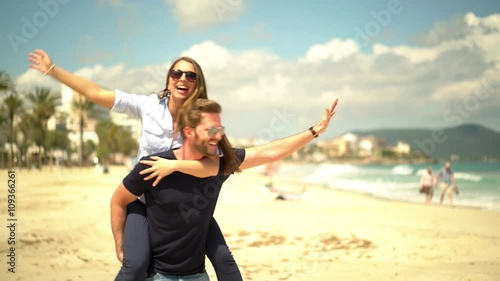 4k footage, young happy woman piggyback on her boyfriend, walking and turning on sunny day in spring on the beach
