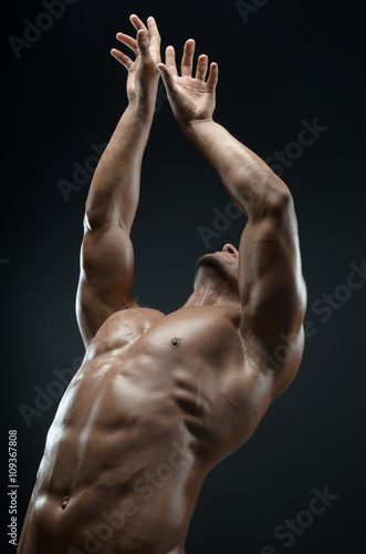 Bodybuilder and strip theme: beautiful with pumped muscles naked man posing in the studio on a dark background