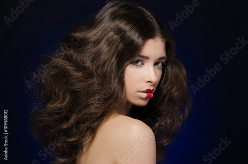 Hair and make-up topic: a very beautiful girl model with lush hair and creative make-up on blue background